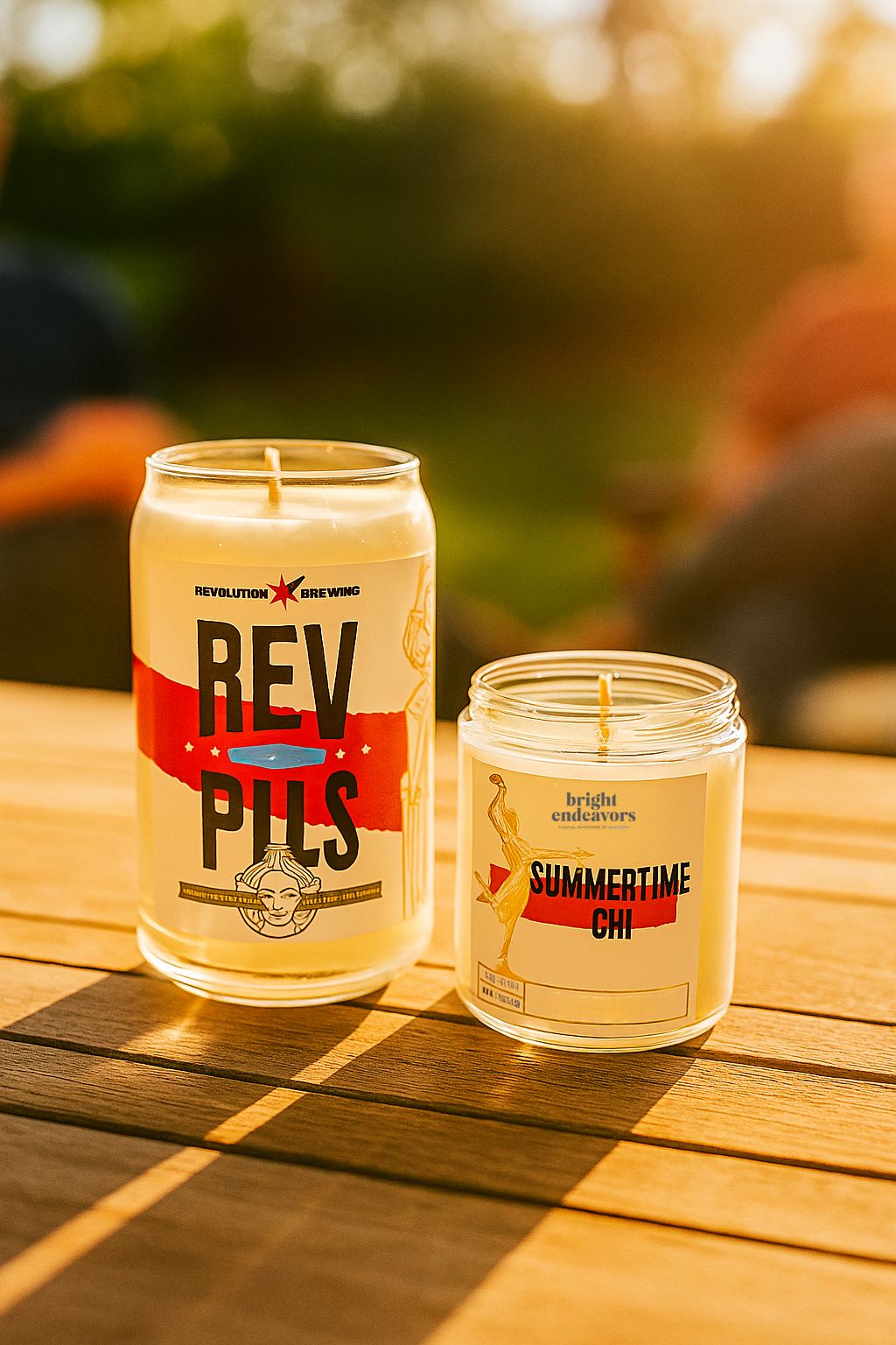 Two candles with labels on a wooden surface outdoors